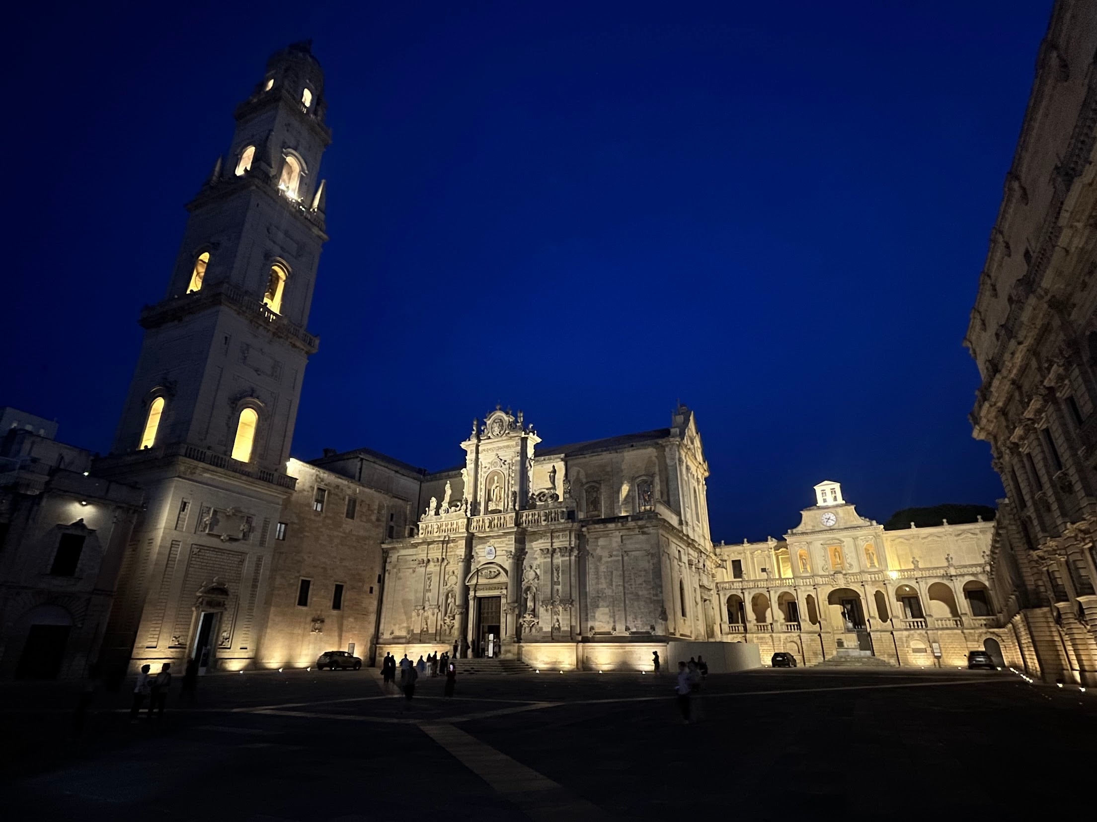 Piazza del Duomo in Lecce lit up at dusk, with the bell tower and the baroque cathedral facade
